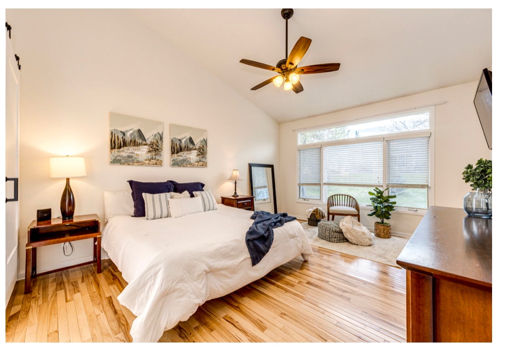 Caleridge Court primary bedroom with warm wood floors, crisp bedding, and balanced bedside styling