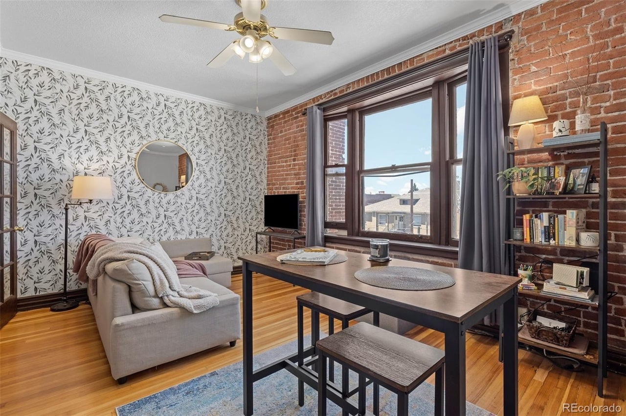 Humboldt Street living and dining room with exposed brick, original wood trim, and soft plum accents