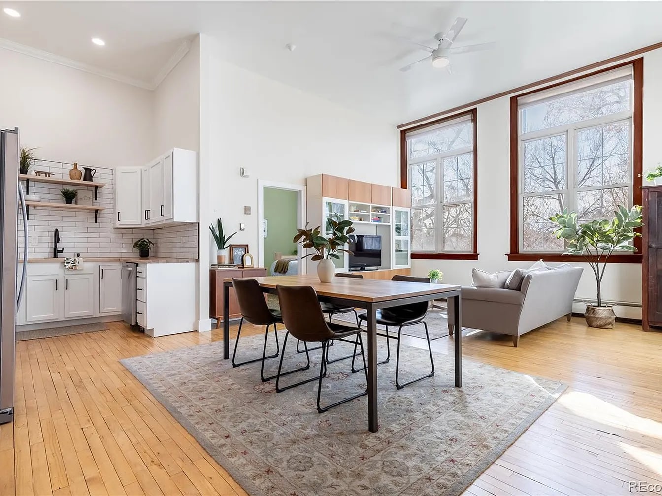 Bright open living and dining room with warm wood details, greenery, and layered neutral furniture