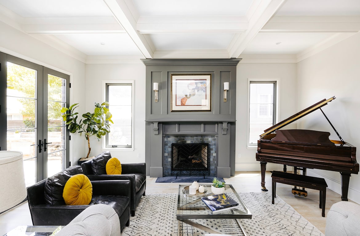 Vine Street living room with a dark fireplace, grand piano, patterned rug, and sculptural lighting